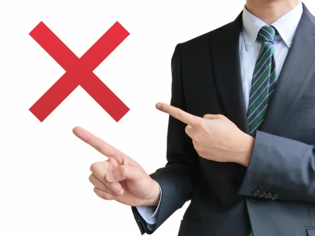 否定の印を指し示すスーツ姿の男性